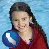 california a little girl wrapped in a dark red towel, in front of a swimming pool