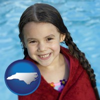 north-carolina map icon and a little girl wrapped in a dark red towel, in front of a swimming pool