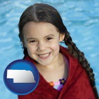 nebraska map icon and a little girl wrapped in a dark red towel, in front of a swimming pool