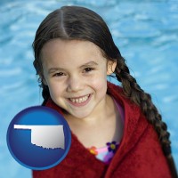 oklahoma map icon and a little girl wrapped in a dark red towel, in front of a swimming pool