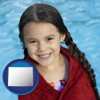 wyoming map icon and a little girl wrapped in a dark red towel, in front of a swimming pool