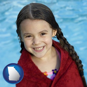 a little girl wrapped in a dark red towel, in front of a swimming pool - with Georgia icon