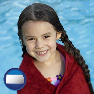 a little girl wrapped in a dark red towel, in front of a swimming pool - with Kansas icon