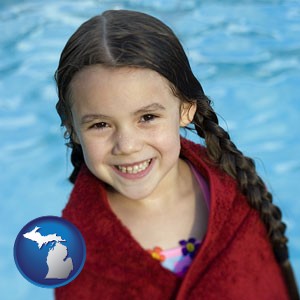 a little girl wrapped in a dark red towel, in front of a swimming pool - with Michigan icon