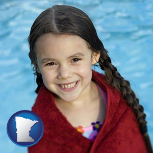 a little girl wrapped in a dark red towel, in front of a swimming pool - with Minnesota icon