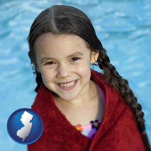 a little girl wrapped in a dark red towel, in front of a swimming pool - with New Jersey icon