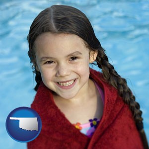 a little girl wrapped in a dark red towel, in front of a swimming pool - with Oklahoma icon