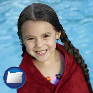 a little girl wrapped in a dark red towel, in front of a swimming pool - with Oregon icon