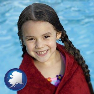 a little girl wrapped in a dark red towel, in front of a swimming pool - with Alaska icon