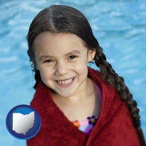 a little girl wrapped in a dark red towel, in front of a swimming pool - with Ohio icon